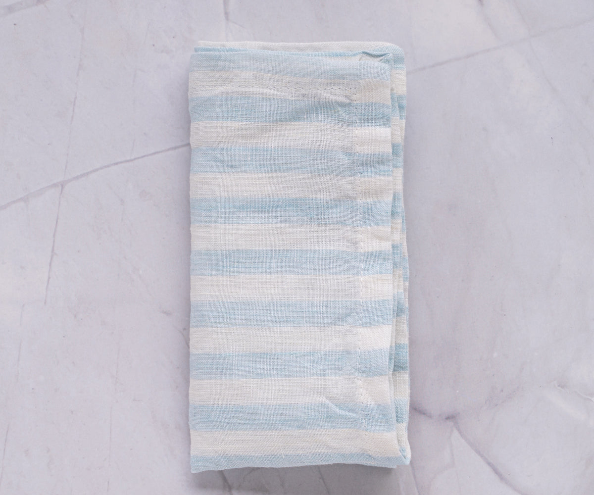 A blue and white striped linen napkin casually placed on a textured marble surface
