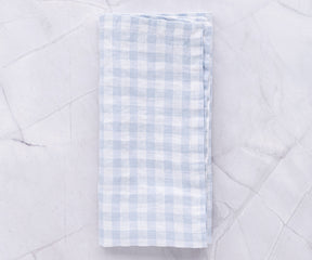 Blue and white gingham linen napkin arranged on a marble countertop
