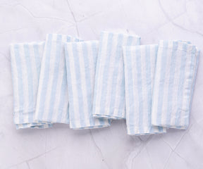 A quartet of linen striped napkins in blue and white arranged on stone