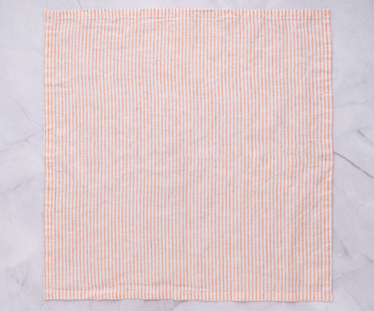 A pink and white striped linen napkin displayed on a marble countertop
