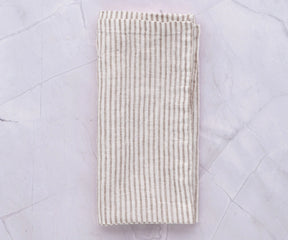 Set of 12 natural linen napkins with classic striped design laid on a rustic table