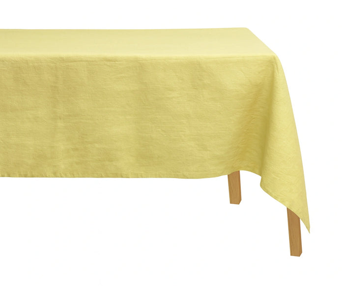 Butter yellow 100% linen rectangular tablecloth displayed on a dining table, adding a soft and elegant touch to the setup.