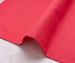 Soft maroon fabric napkin paired with gold cutlery and neutral dinnerware.