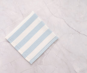 Set of pale blue cotton napkins with cabana stripe, perfect for indoor and outdoor dining.
