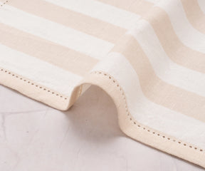 Soft beige cotton napkins with cabana stripe design on a dining table.
