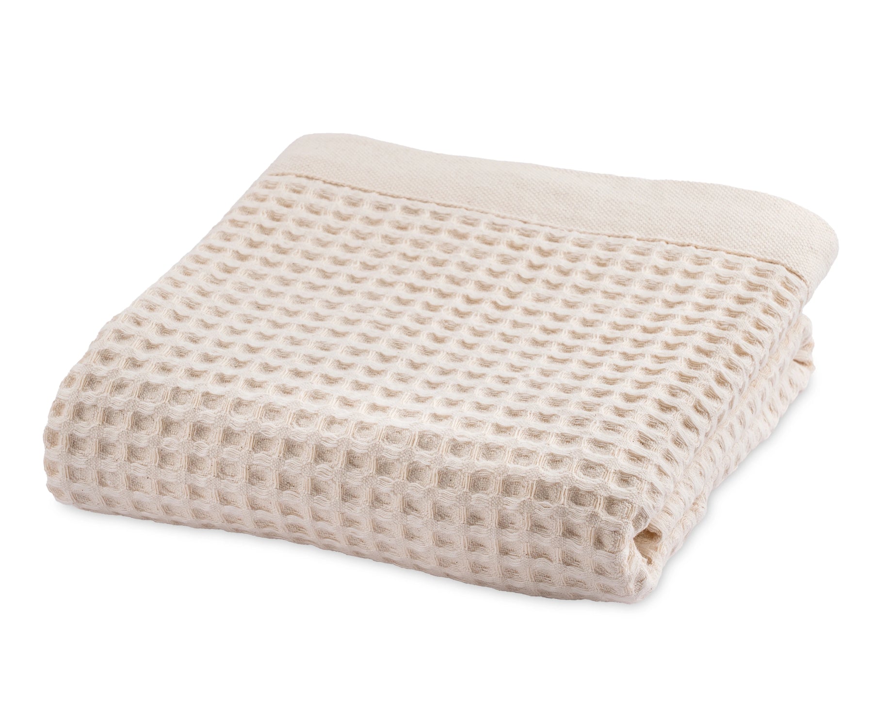 Natural cotton waffle blanket folded neatly on a bed with neutral bedding.