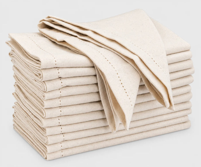 Stack of natural hemstitched cotton cloth napkins folded on a white background