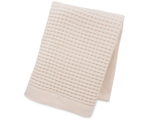 Soft waffle weave blanket in natural tone draped over a cozy sofa.