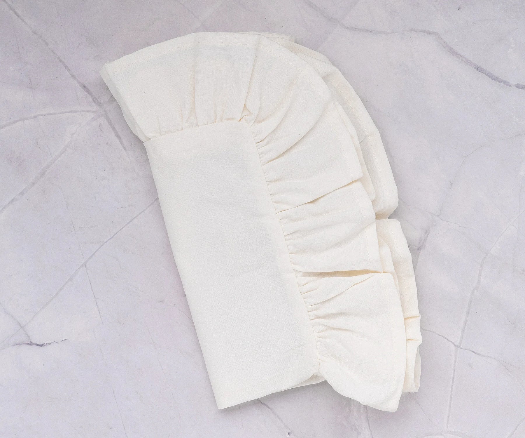 Ruffled cotton napkins layered with an embroidered tablecloth for cozy dining.