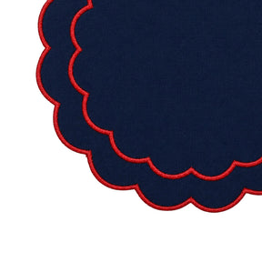 Round cotton table placemats with embroidered detailing and a decorative scalloped border