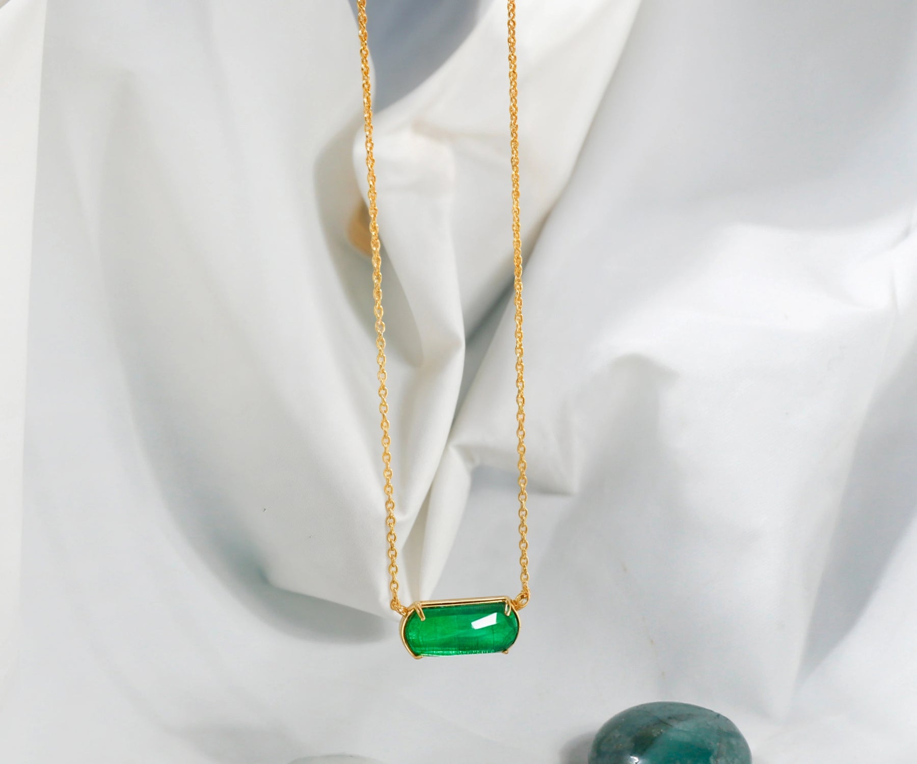 Gold chain necklace with emerald green quartz pendant.
