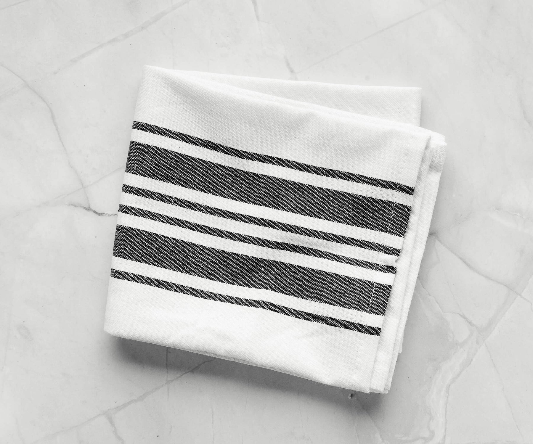 Black kitchen towel with white stripes on a marble countertop