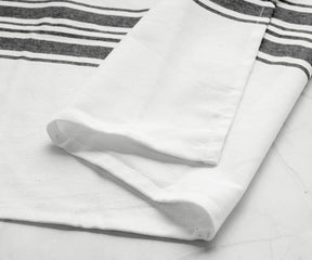 Single black kitchen towel with white stripes on marble background