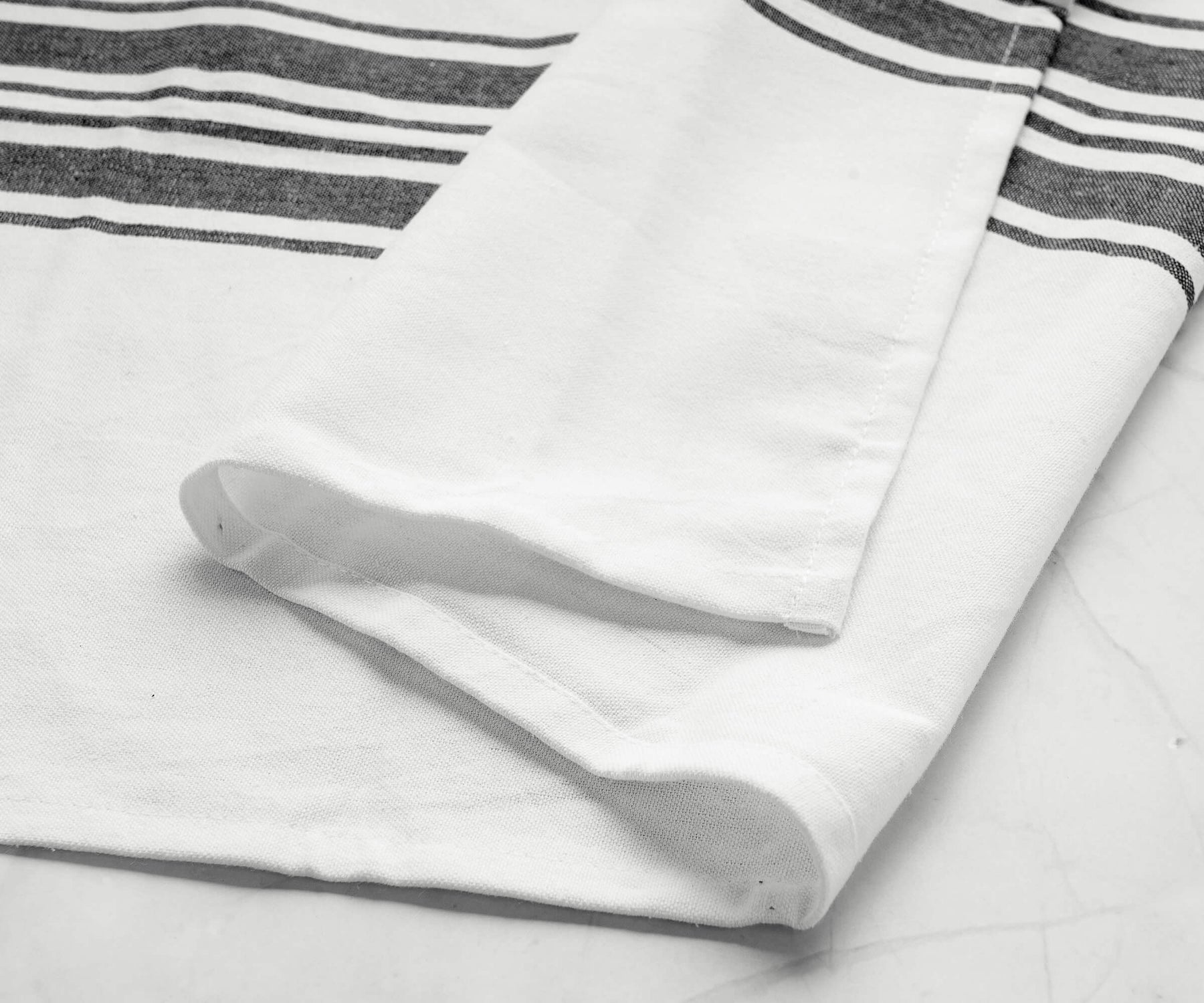 Single kitchen towel featuring black and white stripes on a marble countertop