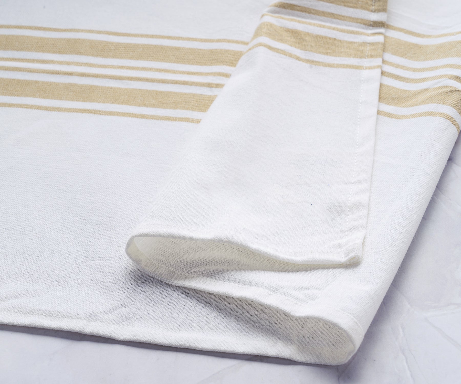 A single kitchen towel adorned with elegant gold stripes on a white fabric