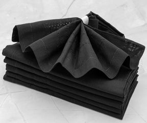 Elegant black napkins neatly folded and placed on a dining table, adding a touch of sophistication to the setting