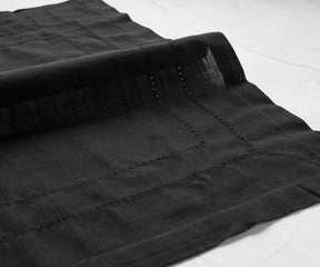 Neatly folded black dinner napkins set beside crystal glasses, adding a sophisticated flair to the table setting.