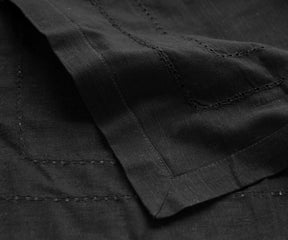 Cotton Black napkins draped over the edge of a table, providing a bold and stylish accent to the dining decor.