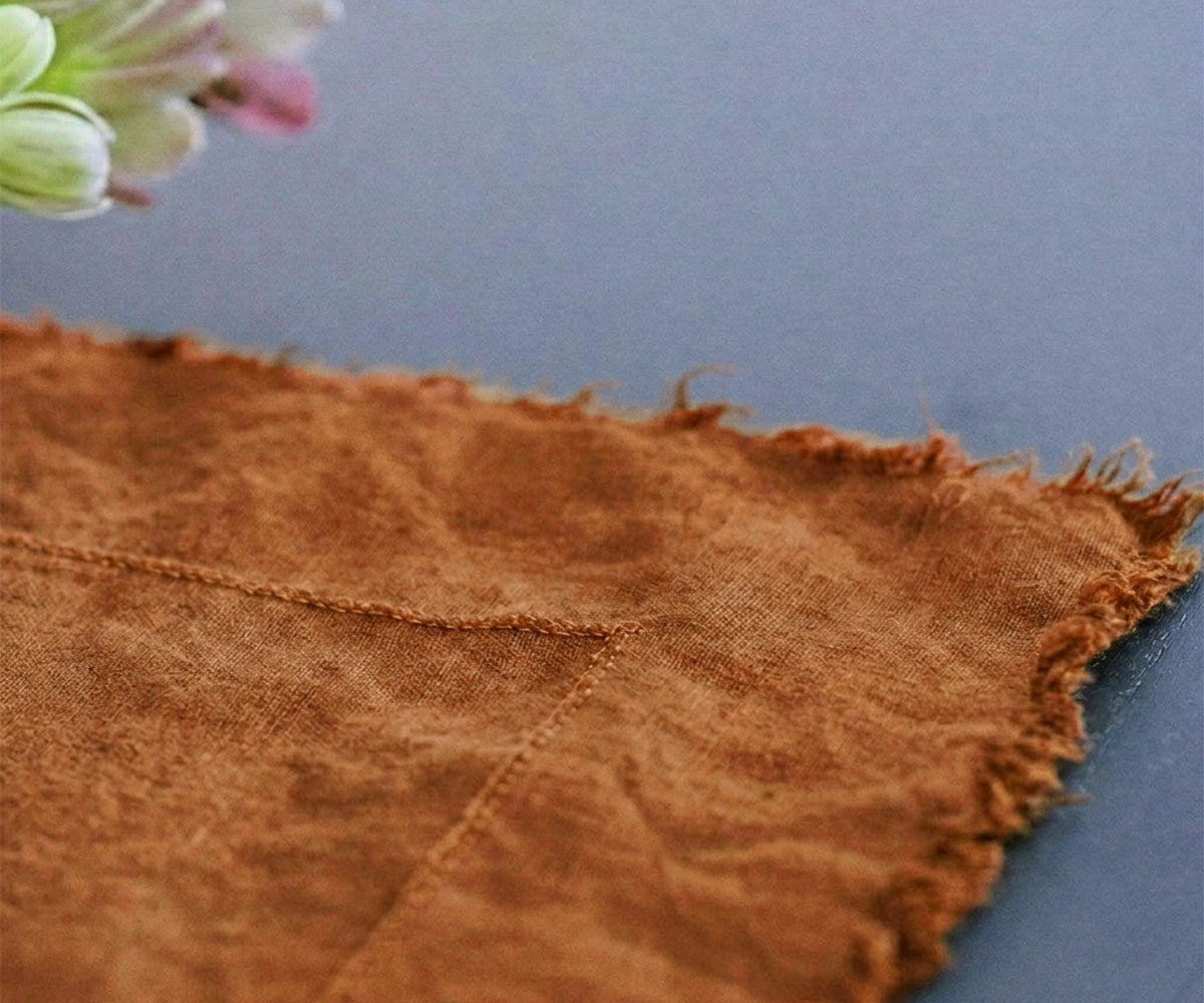 Terracotta linen tablecloth in 100% flax linen with raw edge finish draped over dining table for rustic farmhouse table decor
