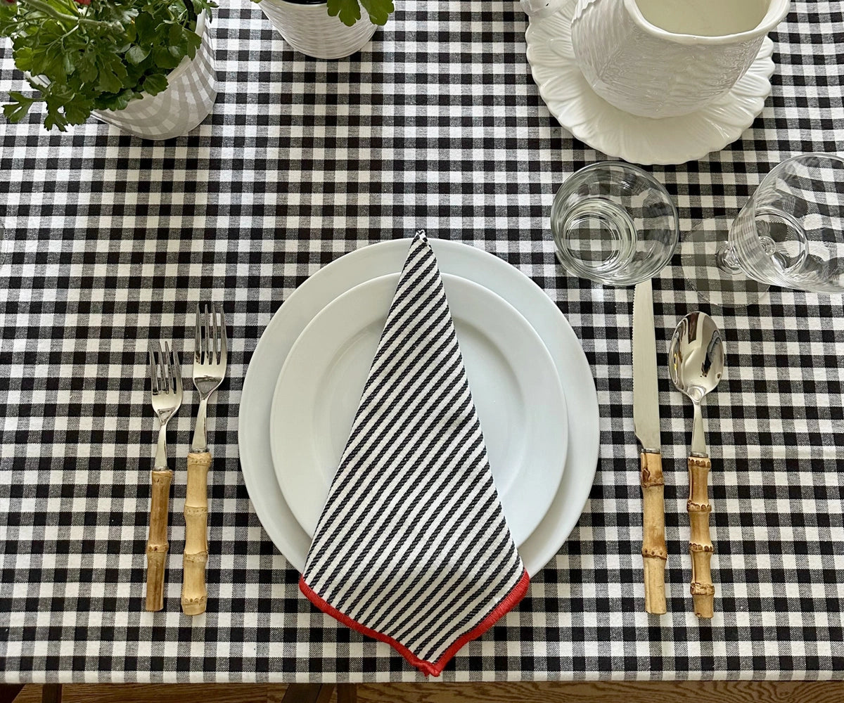 Black and red bordered cotton napkin arranged stylishly for a modern dinner table setting.