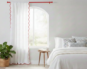 White curtain with Red wavy side trim in a bedroom setting