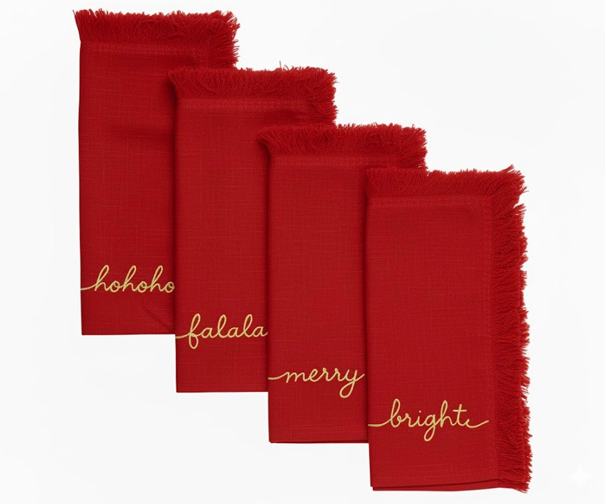 Festive red embroidered napkins with gold lettering and fringed edges for holiday table decoration