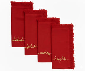 Festive red embroidered napkins with gold lettering and fringed edges for holiday table decoration