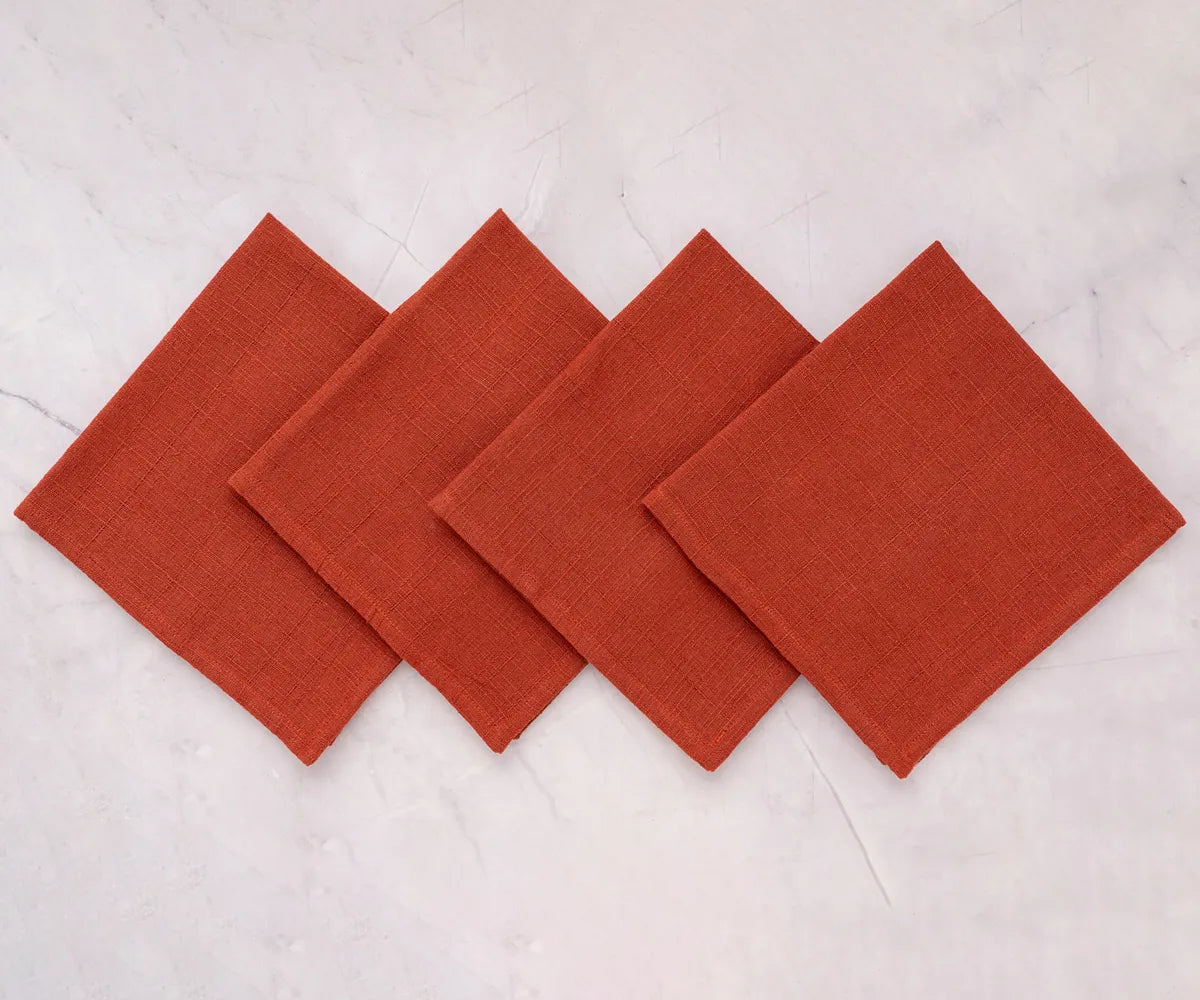 Rust cotton reusable dinner napkins styled with a rustic wooden charger and seasonal centerpiece for a cozy table setting