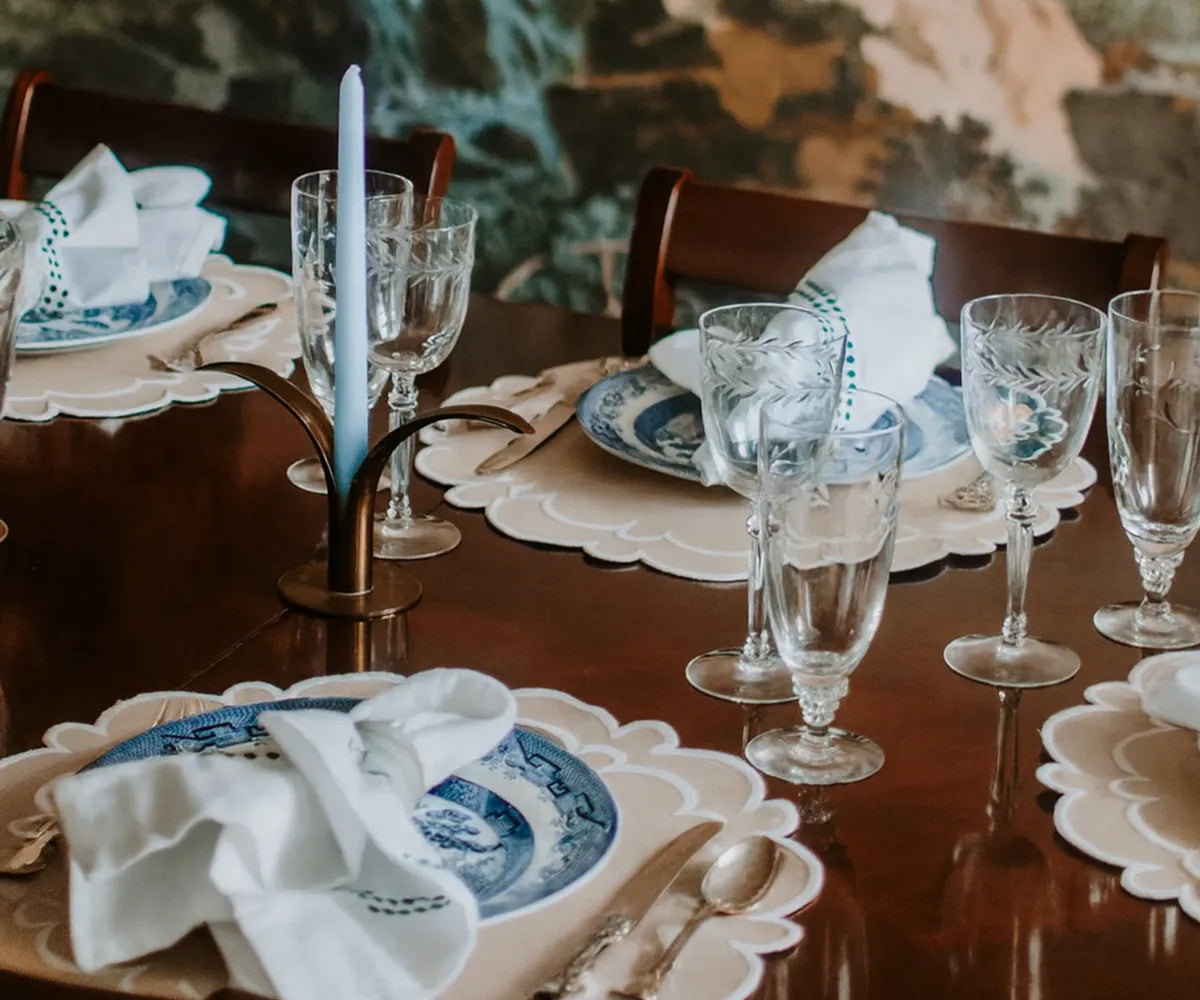 Set of four round beige scalloped placemats made from 100% cotton.