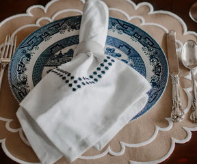Decorative beige scalloped placemats with white trim, 17-inch and 15-inch sizes.