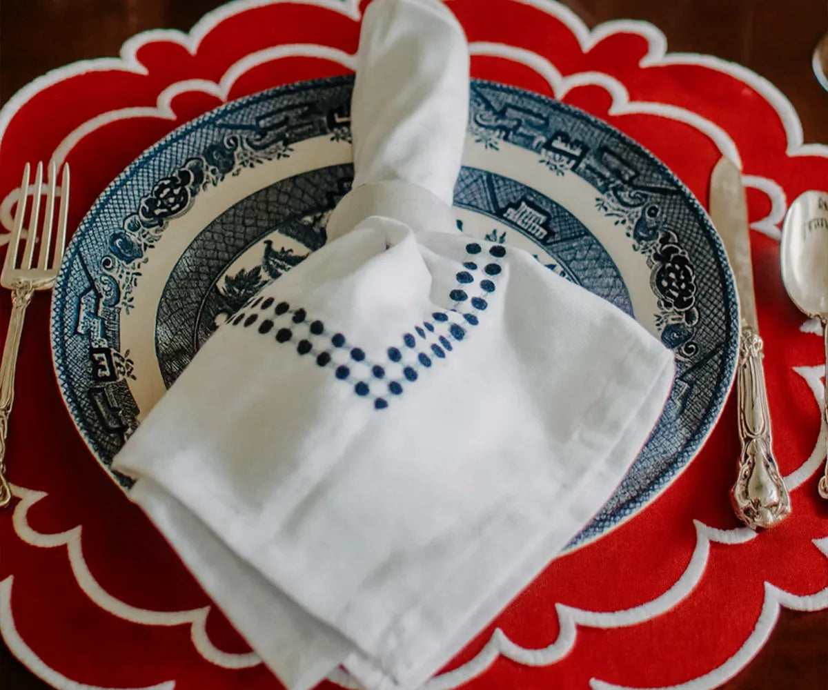 Set of four round red scalloped placemats made from 100% cotton.