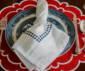 Set of four round red scalloped placemats made from 100% cotton.