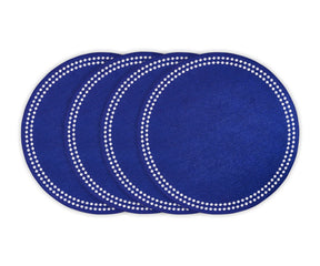 Blue cotton round placemat with white embroidered dot trim on a dining table