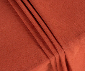 Rich rust cotton rectangle tablecloth neatly spread on a wooden table, paired with neutral runners, wooden chargers, and seasonal centerpieces for a stylish tablescape.