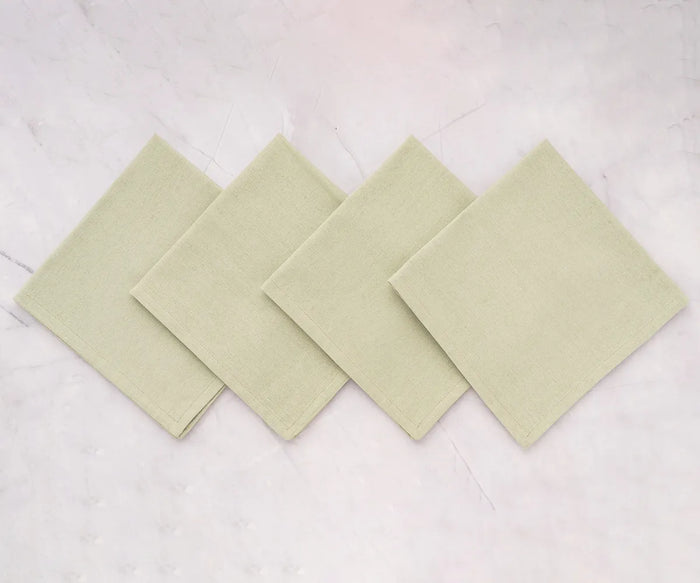 Elegant sage green cotton dinner napkin neatly folded on a rustic dining table with striped tablecloth and classic dinnerware