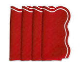 Folded red scalloped cotton napkins on a wooden dining table, ready for a festive meal.
