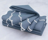 Dusty blue cotton napkins with white scalloped border neatly folded for table setting