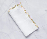Beige scalloped cotton napkins with elegant double-scalloped embroidery on a dining table