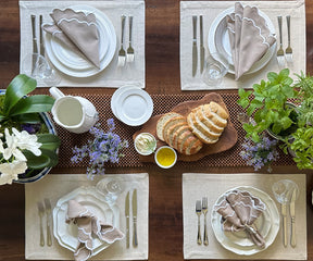 Artfully folded beige scallop napkins set for a high tea gathering.