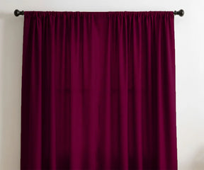 Burgundy velvet curtains hanging on black curtain rod in modern living room