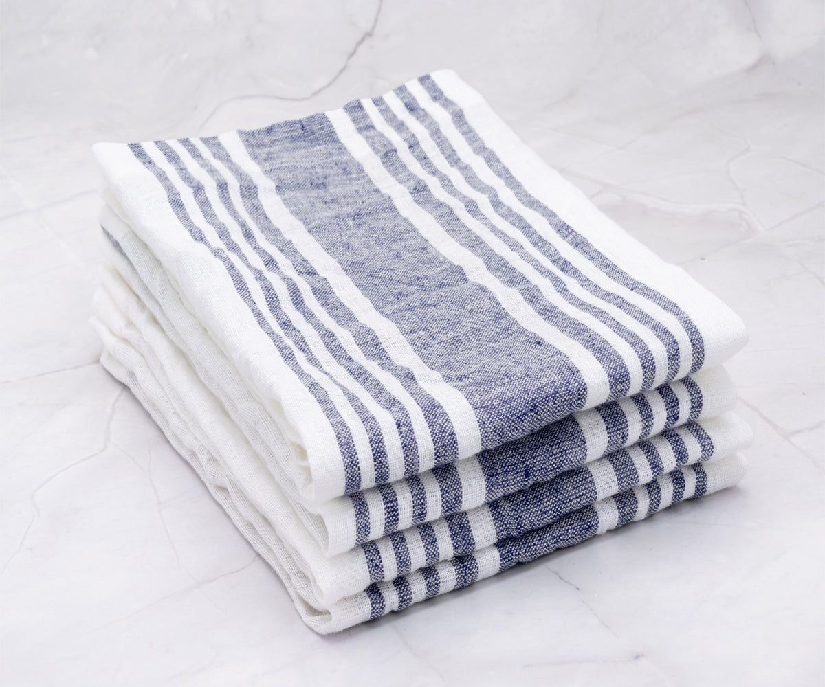 Four neatly stacked linen dinner napkins with blue stripes