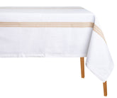 A white rectangular cotton tablecloth with a striped pattern on the edge, displayed on a table with wooden legs.