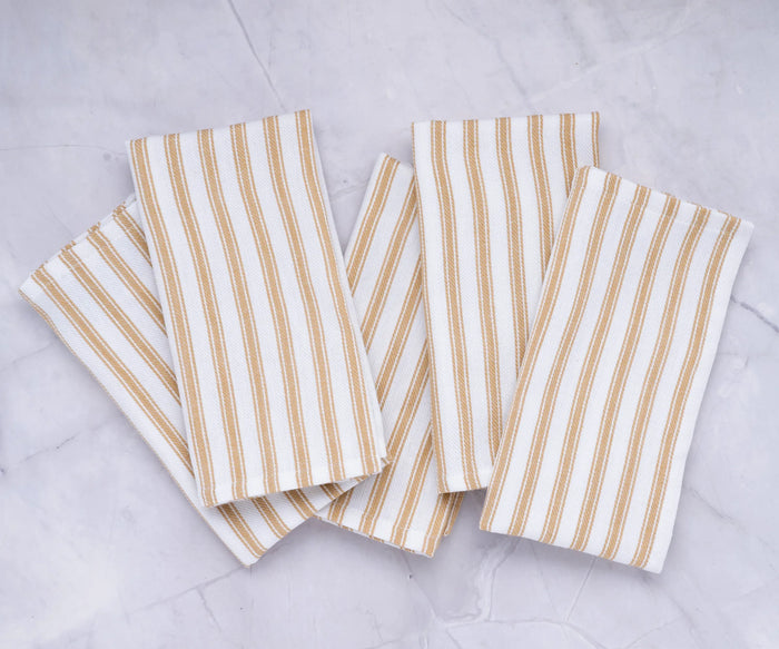 Beige cotton cloth napkins with white vertical stripes displayed on a dining table