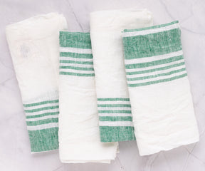Trio of green-striped linen napkins on a polished marble countertop