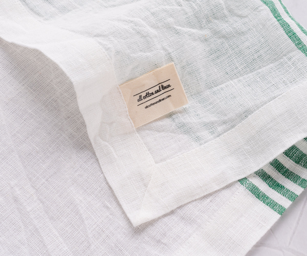 White linen dinner napkin adorned with green stripes
