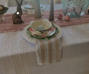 Decorative table setting with a floral bowl and plates on a striped tablecloth.