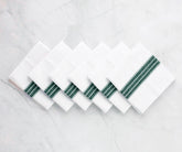 Green and white striped cotton napkin folded neatly on a dining table.