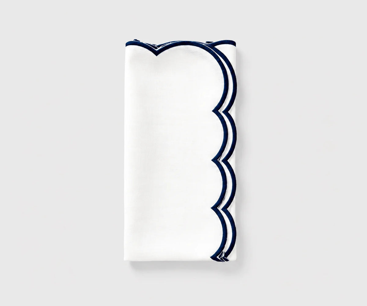 White and navy blue scalloped cloth napkin folded on a white background