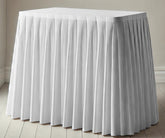 Elegant white cotton table skirt draped around a rectangular table for a wedding setup