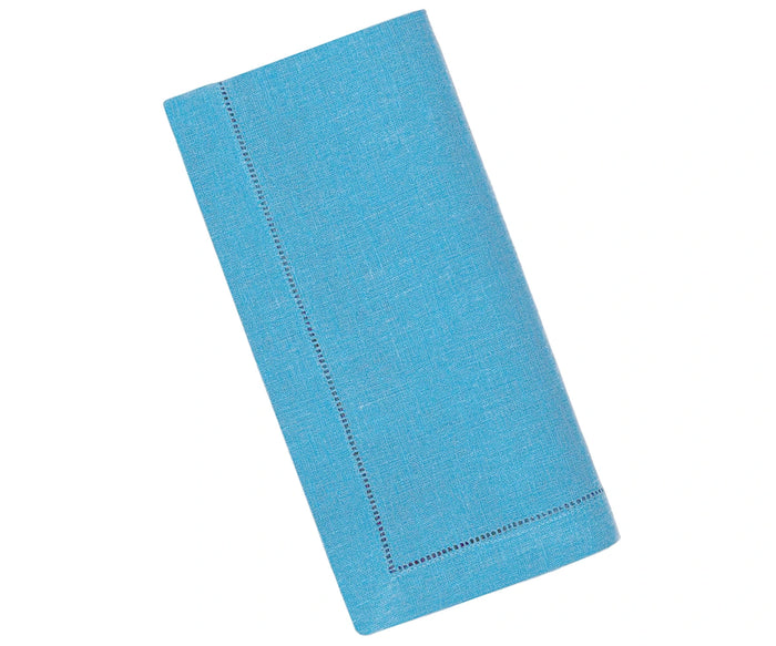 Teal linen napkins with hemstitch detailing neatly folded on a dining table